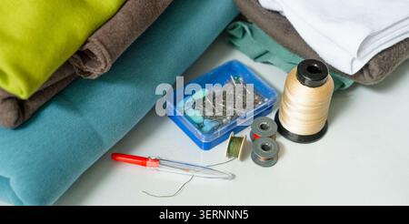Fabrics and threads arranged on white craft workspace as complete sewing kit. Sewing supplies for creative inviting hobby start. Inspiring collection of textile crafting essentials for DIY projects Stock Photo