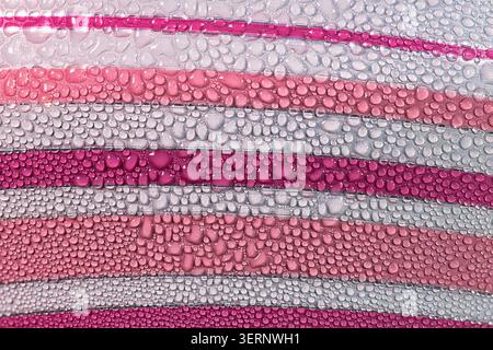 High-detailed macro shot of condensation water droplets on a geometric pink and white striped surface. Perfect abstract background for cosmetic, beaut Stock Photo