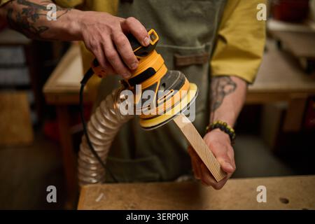 Adult Man Sanding Wood Edge in Carpentry Workshop for Finishing Stock Photo