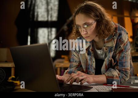 Adult Woman Using Laptop for Carpentry Project Planning Stock Photo