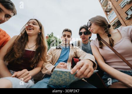 Students studying together outdoors on campus sharing notes and laughing in a group Stock Photo