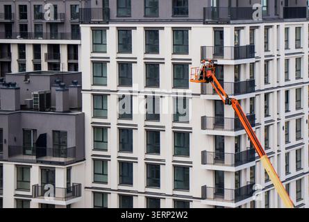 Construction worker in a cherry picker basket repairing an apartment facade Stock Photo