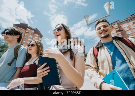 Group of happy students walking on a sunny college campus with notebooks and backpacks Stock Photo