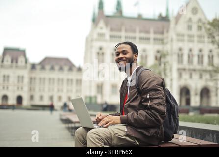 Happy man using laptop outdoors in Budapest Stock Photo