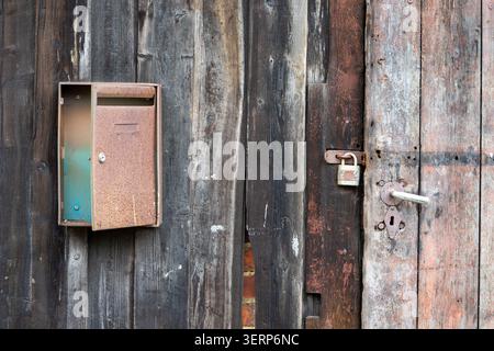 Old mailbox on a wooden door with weathered paint. Stock Photo