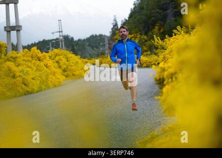 Man running on a rural road surrounded by yellow flowers Stock Photo