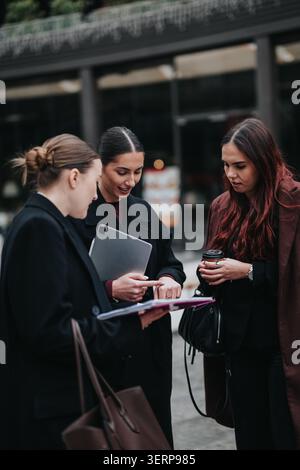 Three professional women having a winter business meeting outdoors with tablet and documents Stock Photo