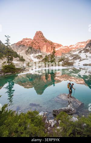 Man explores pristine alpine lake with mountain reflection Stock Photo