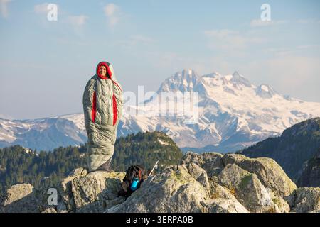 Happy man standing in a sleeping bag on a mountain Stock Photo