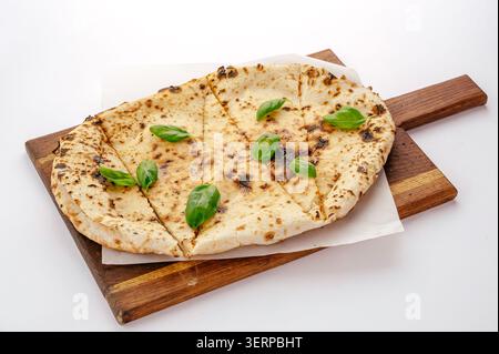 Grilled flatbread with fresh basil on wooden board Stock Photo