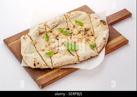 Freshly baked flatbread sliced and served with basil Stock Photo