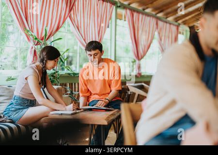High school students studying together in a bright cozy cafe with notebooks and laptops Stock Photo