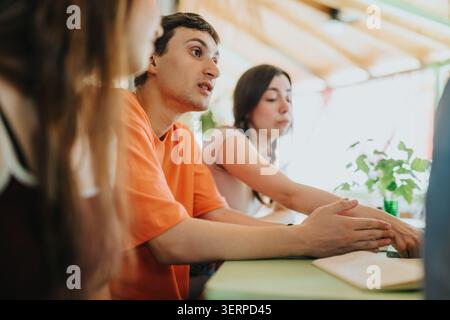 High school students engaged in a focused group discussion at a classroom table Stock Photo