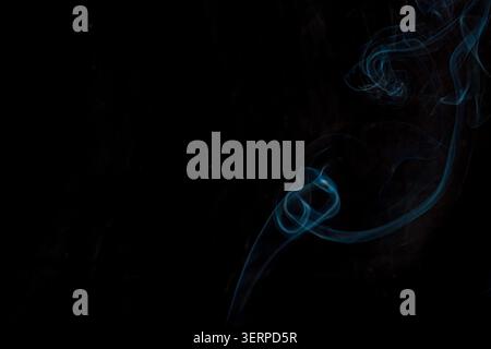 Blue smoke swirling on a black background, soft wisps, dark minimal composition, copy space  Stock Photo