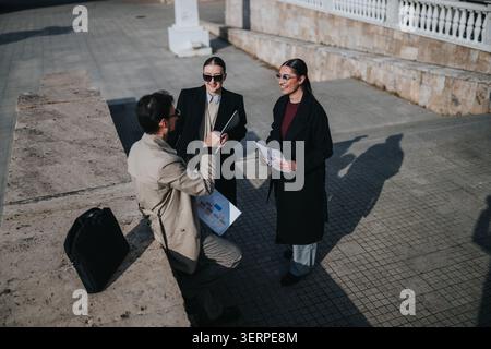Three colleagues having a casual winter business meeting outdoors by a stone plaza in coats Stock Photo