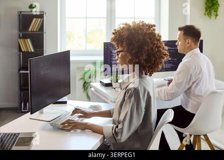 Programmers working on code in bright office, dual monitors and collaboration Stock Photo