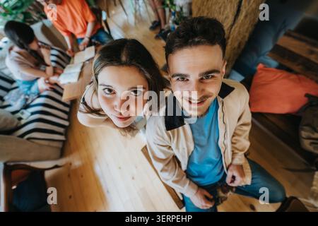 Two high school students smiling up at camera in a casual study group at home Stock Photo