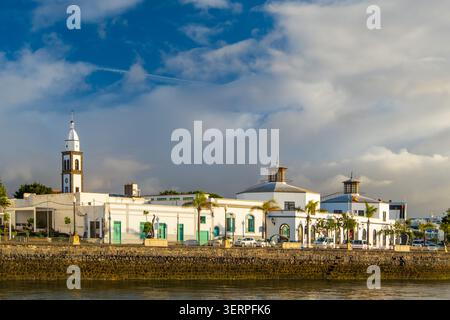 Arrecife Lanzarote waterfront view featuring historical buildings and people leisurely walking along the promenade. The serene atmosphere and clear Stock Photo