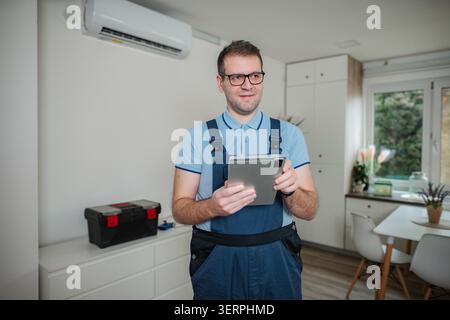 Handyman using digital tablet while repairing air conditioner Stock Photo