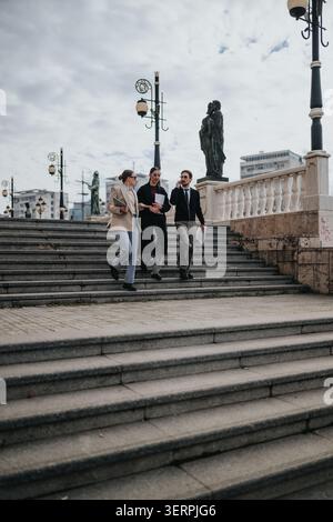 Three business colleagues walking down outdoor steps during a winter business meeting in the city Stock Photo