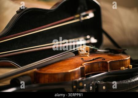 Close up of violin resting in open case with bows, representing music study, instrument practice, classical education. Suitable for music school, lesson, training marketing Stock Photo