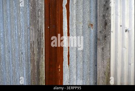 Close up of reclaimed corrugated panel surface with weathered silver metal, rusted corrugated panel, white painted panel Stock Photo