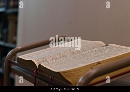 Open dictionary resting on a reading stand in a quiet indoor study setting, showing printed definitions and supporting language learning and reference Stock Photo