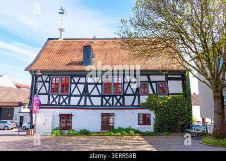 Rosdorf, Germany - April 15, 2026: Historic half-timbered architecture features red-framed windows and an old weather vane atop its tiled roof while o Stock Photo