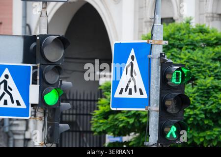 Bright green traffic signals call for pedestrians to cross the street calmly. Stock Photo