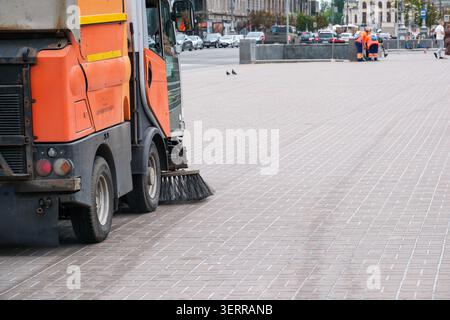 Workers use a street sweeper to tidy up the city streets in the morning light. Stock Photo