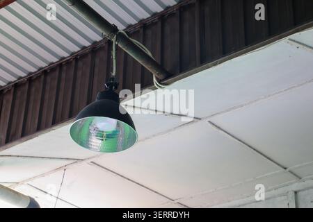 Industrial Hanging LED Lamp Under Metal Roof Ceiling with Electrical Wiring, Modern Warehouse and Workshop Lighting Fixture Concept Stock Photo