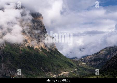 Clouds surround rugged mountain cliffs above Upper Pisang on the Annapurna Circuit in the Manang region of Nepal Himalayas Stock Photo