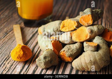 Turmeric roots and powder on wooden table with jar nearby Stock Photo