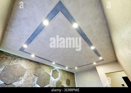 Modern decorative ceiling with recessed spotlights and textured finish, low angle view of stylish interior design. Contemporary lighting, renovation and luxury home concept Stock Photo