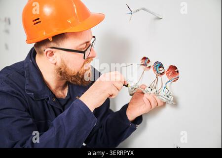 Specialist mounting power outlets and adjusting wiring in wall openings. Indoor construction work, electrical installation and home upgrade concept Stock Photo