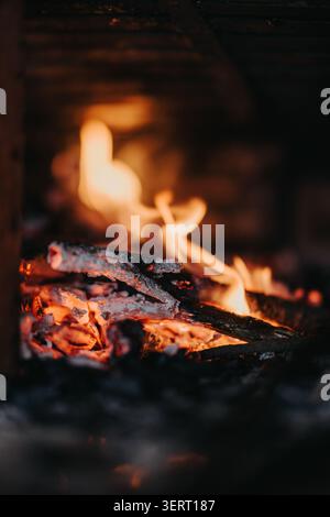 Close-up of burning wood and glowing embers in a warm fireplace with dancing flames Stock Photo