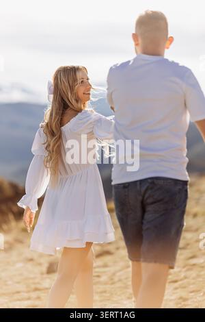 Happy young couple walking together in mountains at sunset Stock Photo