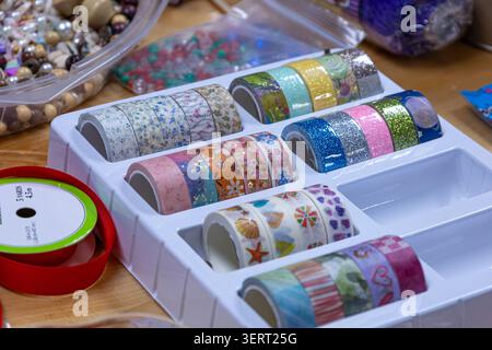Colorful ribbons arranged in a white tray with beads and craft supplies in a creative workspace. Stock Photo