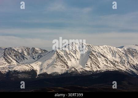 Snow covered mountain range under dramatic cloudy sky Stock Photo