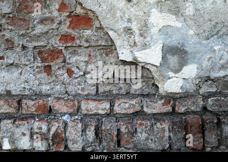 Grunge texture of a half-plastered damaged brick wall Stock Photo