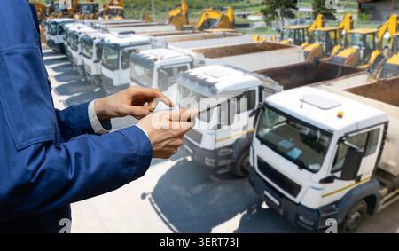 Engineer or site manager using a digital tablet with heavy machinery in the background. Stock Photo