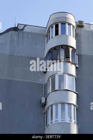 Urban building facade showcasing a modern architectural style with a stacked column of bay windows and small air conditioning units attached to the co Stock Photo