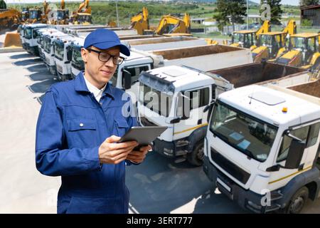 Engineer or site manager using a digital tablet with heavy machinery in the background Stock Photo