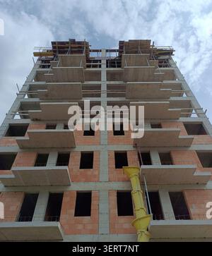 Unfinished high rise residential building framing against a cloudy sky, showcasing the ongoing urban development and construction process with concret Stock Photo