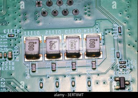 Macro detail of green printed circuit board with surface-mount components and circuitry. Stock Photo