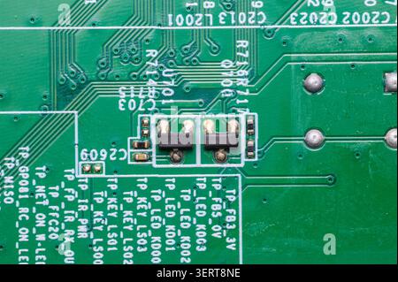 Close-up of a green circuit board showing traces, solder, and various electronic components. Stock Photo