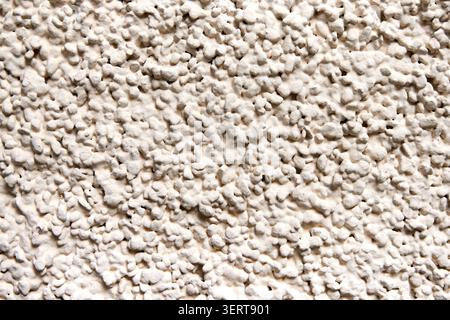 Close-up texture of rough beige stucco wall background with a bumpy pebble dash finish. Stock Photo
