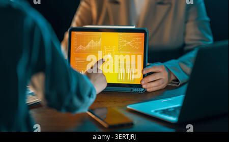 Dynamic business scene featuring professionals collaborating with advanced artificial intelligence analytics on a tablet. Vibrant digital dashboard di Stock Photo