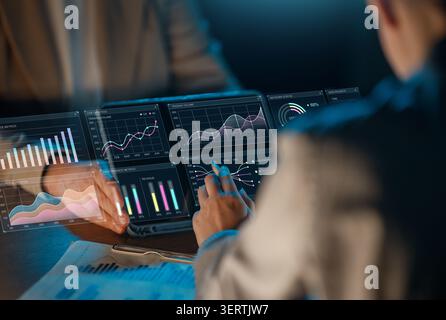 Dynamic image capturing professionals collaborating over futuristic digital interfaces displaying interactive financial graphs, business analytics, an Stock Photo