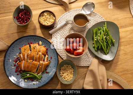 Blue ceramic plate holding sliced stuffed roast is resting on warm wood table near gravy pitcher Stock Photo